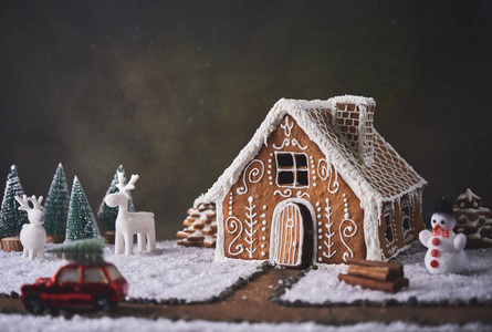 自制姜饼屋。圣诞节的概念。姜饼屋, 饼干, 小汽车玩具与树和鹿与圣诞树在背景
