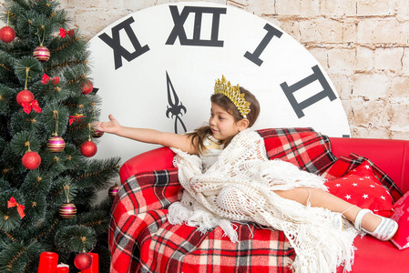 孩子，一个小女孩坐在附近的一个穿着考究的圣诞树和拆开礼物