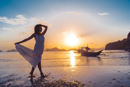 在菲律宾巴拉望岛日落时海滩上的剪影妇女和传统菲律宾船只。el nido 的日落。在日落的时候跳舞。女性在日落, 剪影