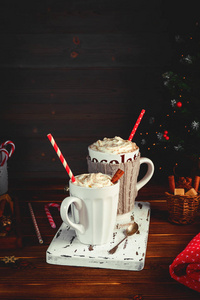 温馨的圣诞作文。两杯热饮料, 巧克力与奶油和卡布奇诺与肉桂棒在黑暗的木质背景。冷冬天的甜蜜款待