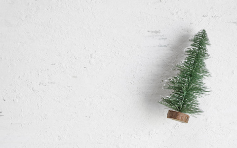 在质朴的白色木桌上的迷你圣诞树木头平躺顶部视图。寒假节日贺卡。文本或设计的空白空间