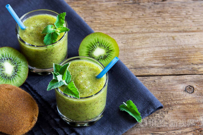 绿色猕猴桃冰沙与薄荷叶玻璃在质朴的木质背景与复制空间