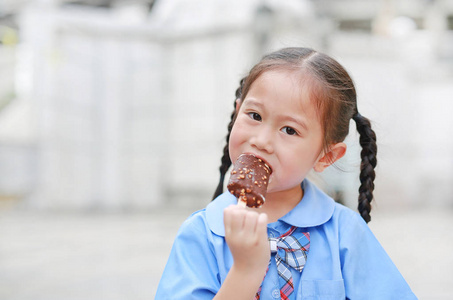 穿着校服的亚洲小女孩的肖像喜欢吃美味的巧克力香草冰淇淋