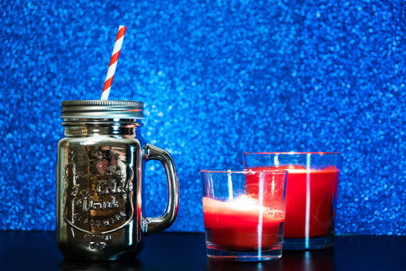 银梅森罐与红稻草在蓝色模糊闪光灯背景。圣诞气氛