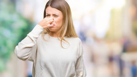 臭东西年轻的美丽的女人休闲白色毛衣在孤立的背景嗅到的东西臭气熏天