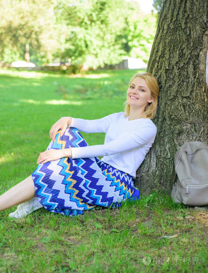 女孩坐在草地上靠在树干上放松在阴影绿色自然背