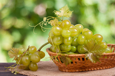 绿色的葡萄在柳条篮子里的木桌上模糊的背景上