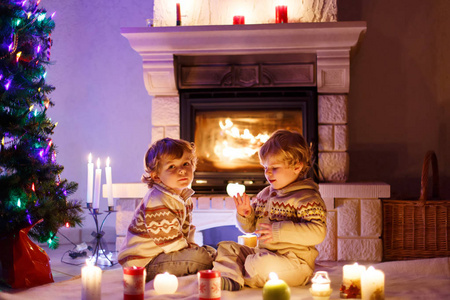 可爱的蹒跚学步的男孩, 金发的双胞胎一起玩耍, lookinig 在烟囱着火。家庭庆祝圣诞假期