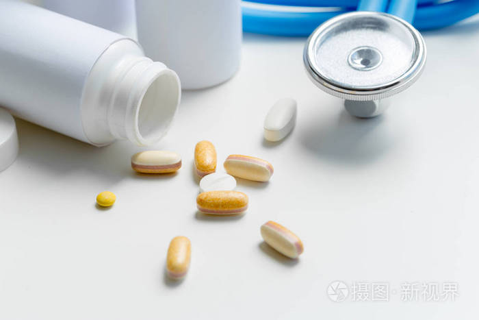 药片或胶囊和听诊器在白色桌上。概念保健