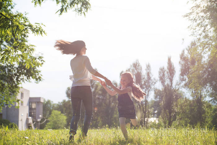 妈妈和女儿手牵手在草坪上旋转