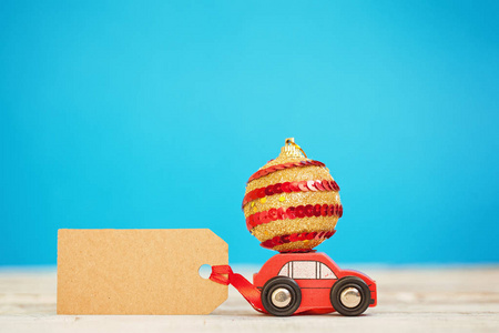 微型红色汽车携带一个蓝色背景的圣诞礼品盒。圣诞节和新年的概念