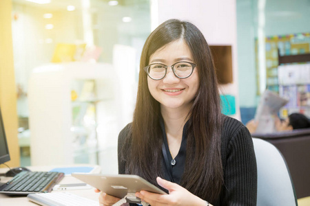 微笑在现代的办公室，电信概念使用数字平板的亚洲年轻女性