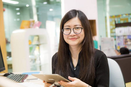 年轻的办公室女性使用数字平板电脑在图书馆的业务学习