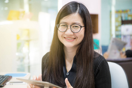 微笑着用数字平板电脑在现代的亚洲年轻女性