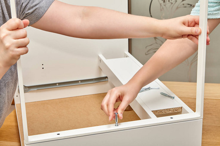 艾伦关键杂工用螺丝固定抽屉的一部分, 其中一个把螺丝拉紧到木桌表面