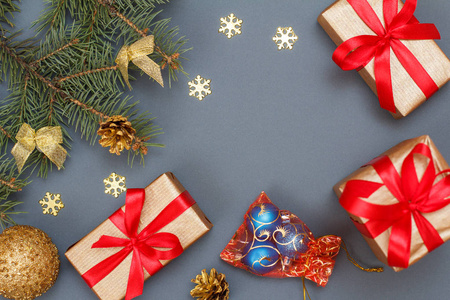 圣诞装饰。礼品盒, 玩具球, 天然冷杉树枝与锥在灰色的背景。顶部视图。圣诞贺卡概念