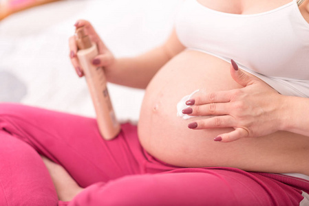 孕妇用奶油涂抹在腹部的伸展痕上