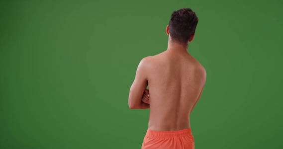 身穿泳衣的拉丁裔男子在绿色屏幕上向外看距离的后视