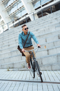 时尚中年男子在太阳镜骑自行车在街上