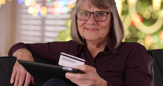 快乐的女士与平板电脑和信用卡准备购买圣诞礼物在互联网上