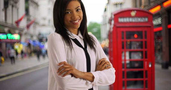 伦敦街头电话亭附近欢快的黑人女商人画像