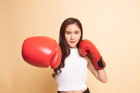 年轻的亚洲妇女与红色拳击手套米色背景