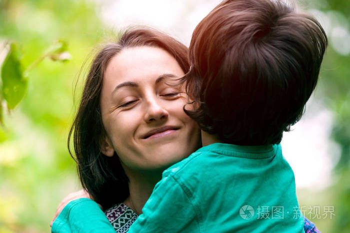 妈妈的怀抱.这个男孩在拥抱他的母亲.微笑的女人和她的儿子在自然界散