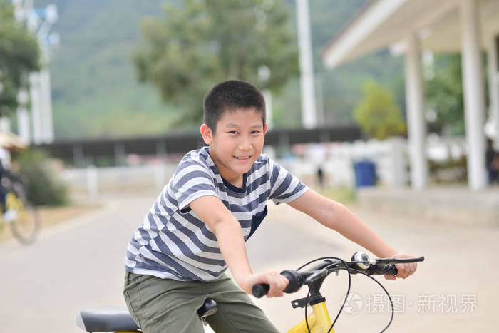 快乐的亚洲男孩骑自行车户外