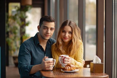 年轻的夫妇约会在咖啡店。恋爱中的男人和女人坐在咖啡馆里, 喝着咖啡