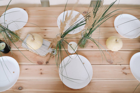 假日餐桌装饰与白色装饰南瓜, 白色板材和蜡烛在木背景。秋天的作文。秋天, 秋天, 万圣节, 感恩节的概念。平面布局, 顶部视图
