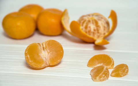 橘子片与整个橘子躺在一个白色的木桌上