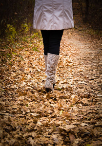 女孩在靴子走在秋叶