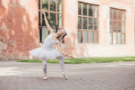 迷人的年轻芭蕾舞女演员在尖鞋跳舞城市街道