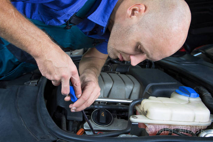 修理汽车发动机发动机的年轻汽车维修技术员
