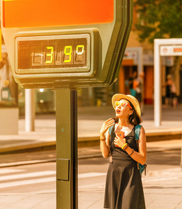 在炎热天气下, 在街道温度计显示39摄氏度的背景下, 妇女在外面遭受高温和中暑
