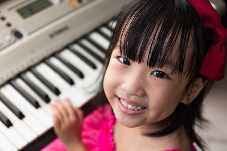 快乐亚洲中国小女孩在玩电钢琴键盘