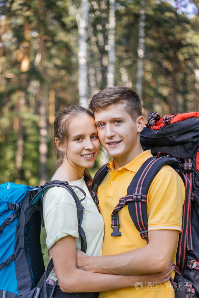 一对背着背包在森林里徒步的游客