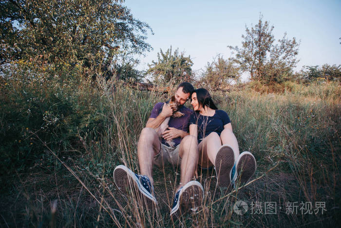 在与他们的狗约克夏草地上年轻快乐 couplesitting