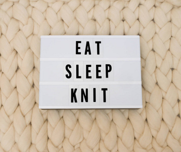 在针织背景的灯箱上吃睡眠针织字。舒适的舒适。针织羊毛背景