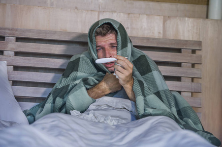 年轻的病人浪费和疲惫的男子躺在家里的床感觉不舒服, 患有感冒和流感打喷嚏鼻子与组织有病毒和头痛在家庭保健和抓手的概念