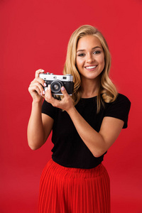 摄影师妇女的画像20多岁举行和拍照在复古照相机查出在红色背景在演播室