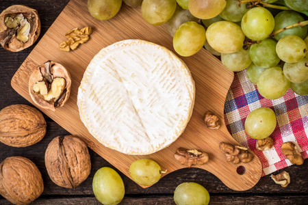 卡门培尔奶酪芝士核桃和绿色葡萄在木制仿古背景