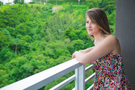 幸福的年轻女人从阳台上看风景