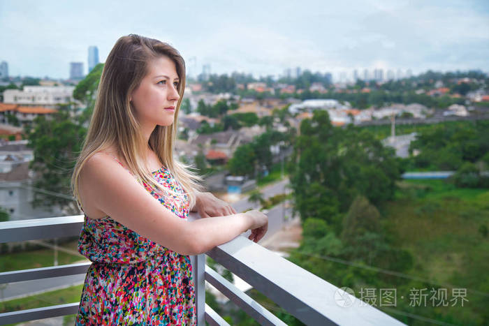 年轻女人从阳台上看风景