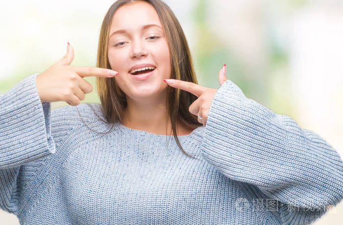 年轻美丽的高加索妇女穿着冬季毛衣在孤立的背景微笑自信显示和指向用