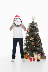 在圣诞老人帽子与时钟站在附近的圣诞树查出的人模糊的视图白色