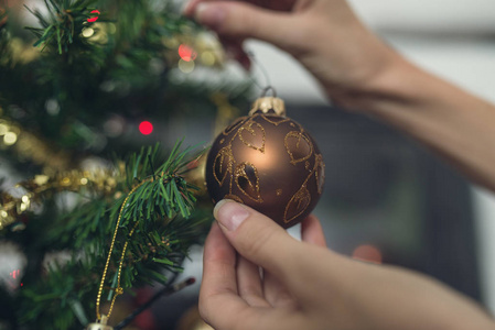 复古形象的女性手挂在圣诞树上闪亮的棕色节日小面包。特写镜头视图