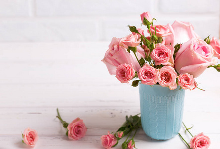 蓝色杯子的粉红玫瑰对白色砖墙