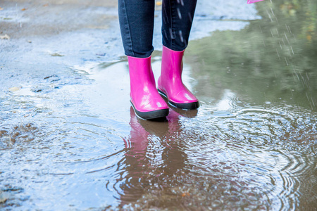 穿着橡胶靴的女人和在雨中行走的雨衣的女人照片