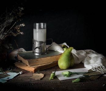 静物,复古.旧的书本,束花,梨,在一张木桌上的牛奶.深色的背景照片